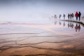 Misty scene of walking tourists on wooden boardwalk inside Grand Prismatic Spring