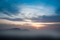 Misty sunrise clouds below mountains tree silhouette Royalty Free Stock Photo