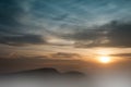Misty sunrise clouds below mountains tree silhouette Royalty Free Stock Photo