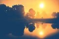 Misty sunrise orange morning near water and windmill