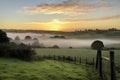 misty sunrise over the rolling hills, with mist still clinging to the ground