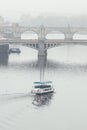 Misty view of bridges over Vltava and small touristic ferry in Prague