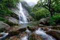 Misty Waterfall Cascading into Rocky Stream in Lush Forest Royalty Free Stock Photo