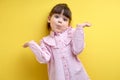 misunderstanding child girl shrugging, i don't know concept. isolated yellow background Royalty Free Stock Photo