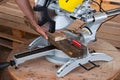 Miter saw for cutting a tree on a wooden table. A man lays down wooden boards. Tool for carpentry Royalty Free Stock Photo