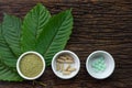 Mitragyna speciosa kratom leaves with medicine products in powder, capsules and tablet in white ceramic bowl with wooden texture