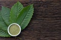 Mitragynina speciosa or Kratom leaves with powder product in white ceramic bowl and wooden table background