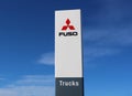 Mitsubishi Fuso Truck and Bus corporation logo outside the dealership of the area, on blue sky background.