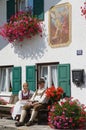 People sit in front of the traditional bavarian house in Mittenwald, Germany.