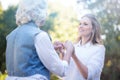 Kind young woman holding hands with grandmother in the park