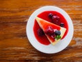 Mix berry cheese cake on white plate on wood background. Royalty Free Stock Photo