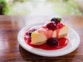 Mix berry cheese cake on white plate on wood background Royalty Free Stock Photo