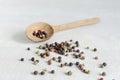 A mix of black, white, red and allspice peppercorns with a wooden spoon on a light background. dried spice peppercorn concept Royalty Free Stock Photo