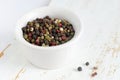 A mix of black, white, red and fragrant peppercorns in a white bowl on a light background. dried spice peppercorn concept Royalty Free Stock Photo