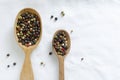 A mix of black, white, red and fragrant peppercorns in two wooden spoons on a light background. dried spice peppercorn concept Royalty Free Stock Photo