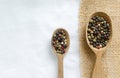 A mix of black, white, red and fragrant peppercorns in two wooden spoons on a light background. dried spice peppercorn concept Royalty Free Stock Photo