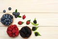 Mix of blueberries, blackberries, raspberries in wooden bowl on light wooden table background Royalty Free Stock Photo