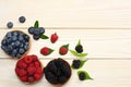 mix of blueberries, blackberries, raspberries in wooden bowl on light wooden table background. top view with copy space Royalty Free Stock Photo