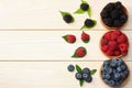 mix of blueberries, blackberries, raspberries in wooden bowl on light wooden table background. top view with copy space Royalty Free Stock Photo