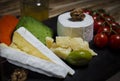 Mix cheese on dark background on wood board with grapes, honey, nuts, tomatoes and basil. Top view Royalty Free Stock Photo