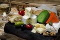 Mix cheese on dark background on wood board with grapes, honey, nuts, tomatoes and basil. Top view Royalty Free Stock Photo