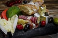 Mix cheese and meat on dark background on wood board with grapes, honey, nuts, tomatoes and basil. Top view. Royalty Free Stock Photo