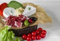 Mix cheese and meat on white background on wood board with grapes, honey, nuts, tomatoes and basil. Top view Royalty Free Stock Photo