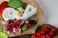 Mix cheese and meat on white background on wood board with grapes, honey, nuts, tomatoes and basil. Top view Royalty Free Stock Photo