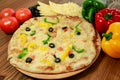 Mix cheese and vegetable pizza with bell pepper, tomato and black olive served in wooden board isolated on table side view of Royalty Free Stock Photo