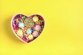 Mix colorful chocolate sweets lie in gift box shape of heart on yellow background Flat lay Royalty Free Stock Photo