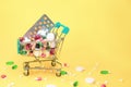 cart full of pills and vitamins on bright yellow background.
