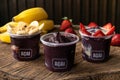 Mix of Delicious Brazilian AÃÂ§aÃÂ­ Cream, in a plastic Cup With a variety of Toppings, in a rustic wooden background. Summer acai