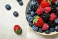 Mix of different fresh berries in bowl on grey table, flat lay. Space for text Royalty Free Stock Photo