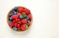 Mix of different fresh berries in bowl on white wooden table, top view. Space for text Royalty Free Stock Photo