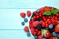 Mix of different fresh berries and mint in bowl on blue wooden table, flat lay. Space for text Royalty Free Stock Photo