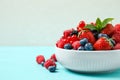 Mix of different fresh berries and mint in bowl on blue wooden table. Space for text Royalty Free Stock Photo