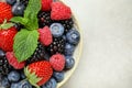 Mix of different fresh berries and mint in bowl on grey table, top view. Space for text Royalty Free Stock Photo