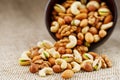 Walnut platter spilled out of the cup on the background of cloth from burlap. Nuts as structure and background, macro Royalty Free Stock Photo