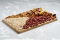 Mix of dried fruits nuts and cereals on a wooden board standing on concrete