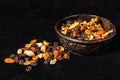 Mix of energetic seeds and dried fruits in a wooden bowl on a black surface. 45 deg. view Royalty Free Stock Photo