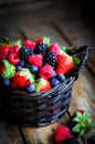 Mix of fresh berries in a basket on rustic wooden background Royalty Free Stock Photo