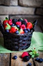 Mix of fresh berries in a basket on rustic wooden background Royalty Free Stock Photo