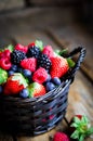 Mix of fresh berries in a basket on rustic wooden background Royalty Free Stock Photo