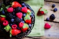 Mix of fresh berries in a basket on rustic wooden background Royalty Free Stock Photo