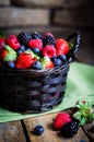 Mix of fresh berries in a basket on rustic wooden background Royalty Free Stock Photo