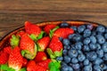 Mix of fresh berries strawberries in a basket on rustic wooden background Royalty Free Stock Photo