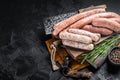 Mix fresh raw sausages. Beef, pork, lamb and chicken mince meat sausages on a butcher cutting board with spices. Black background Royalty Free Stock Photo