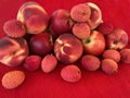 Mix fruit: fresh red peaches, nectarine and lychee on red cloth napkin Royalty Free Stock Photo
