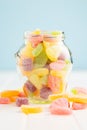 Mix of fruity jelly candy in jar on white table