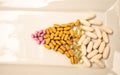 Mix of gold, pink and white gel capsules of vitamin B, vitamin E